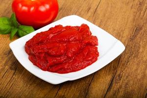 Tomato paste on the plate and wooden background photo