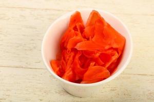 Picked ginger in a bowl on wooden background photo