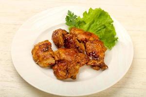 Teriyaki thighs on the plate and wooden background photo