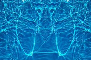 Defocus blurred transparent blue colored clear calm water surface texture with splash, bubble. Shining blue water ripple background. Surface of water in swimming pool. Blue bubble water shining. photo