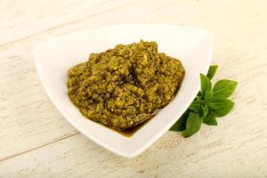 Pesto sauce in a bowl on wooden background photo