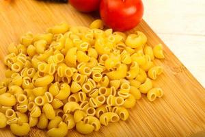 Raw pasta on wooden plate photo