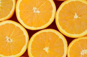 Top view of a several orange fruit slices on bright background in orange color. A saturated citrus texture image photo