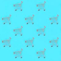 Shopping addiction, shopping lover or shopaholic concept. Many small empty shopping carts perform a pattern on a pastel colored paper background. Flat lay composition, top view photo