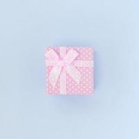Small pink gift box with ribbon lies on a violet background photo
