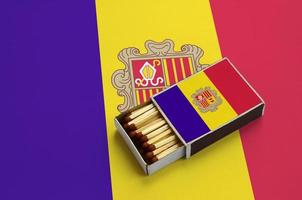 Andorra flag  is shown in an open matchbox, which is filled with matches and lies on a large flag photo