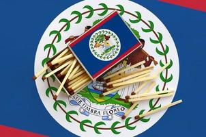 Belize flag  is shown on an open matchbox, from which several matches fall and lies on a large flag photo