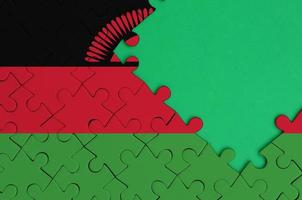 Malawi flag  is depicted on a completed jigsaw puzzle with free green copy space on the right side photo