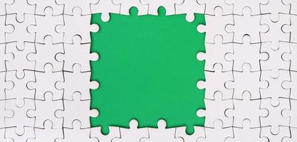 Framing in the form of a rectangle, made of a white jigsaw puzzle around the green space photo