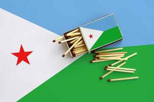 Djibouti flag  is shown on an open matchbox, from which several matches fall and lies on a large flag photo