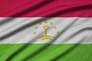 Tajikistan flag  is depicted on a sports cloth fabric with many folds. Sport team banner photo