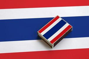 Thailand flag  is pictured on a matchbox that lies on a large flag photo