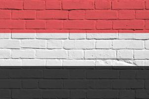 bandera de yemen representada en colores de pintura en la pared de ladrillo antiguo. banner texturizado sobre fondo de mampostería de pared de ladrillo grande foto