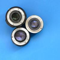 Several photographic lenses lie on a bright blue background. Space for text photo