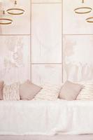 Many pillows lie on the couch, which is covered with a large plush veil against the background of a marble wall photo