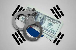 South Korea flag  with handcuffs and a bundle of dollars. Currency corruption in the country. Financial crimes photo