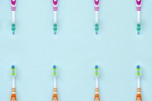 A lot of toothbrushes lie on a pastel blue background. Top view, flat lay. Minimal concept photo