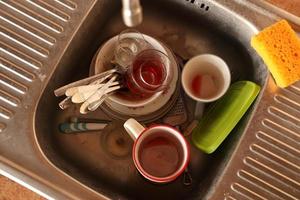 Stack of dirty dishes with food leftovers in the kitchen sink. Unwashed dishes photo