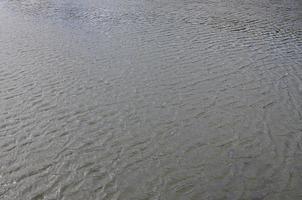 The texture of dark river water under the influence of wind, imprinted in perspective. Horizontal image photo