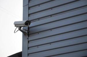 White surveillance camera built into the metal wall of the office building photo