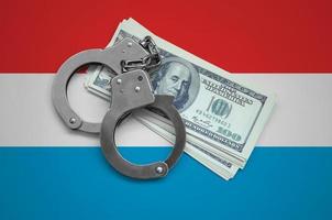 Luxembourg flag  with handcuffs and a bundle of dollars. Currency corruption in the country. Financial crimes photo