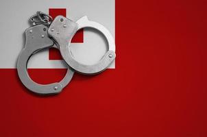 Tonga flag  and police handcuffs. The concept of crime and offenses in the country photo