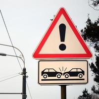 alto riesgo de colisión. una señal de tráfico con un signo de exclamación y dos autos que chocaron entre sí foto