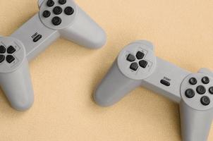 Playing games concept. Two pad joysticks lies on the blanket of furry orange fleece fabric. Controllers for video games on a background texture of light orange soft plush fleece material photo