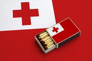 Tonga flag  is shown in an open matchbox, which is filled with matches and lies on a large flag photo
