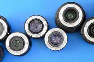 Several photographic lenses lie on a bright blue background. Space for text photo