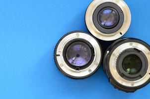 Several photographic lenses lie on a bright blue background. Space for text photo