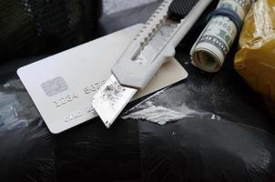 Spoon full of heroin and paper knife lies on drug packs and credit card with dollars roll photo