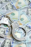 Silver police handcuffs lies on a many dollar bills photo