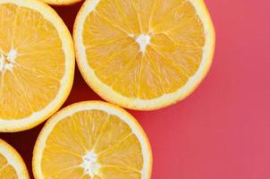 Top view of a several orange fruit slices on bright background in red color. A saturated citrus texture image photo