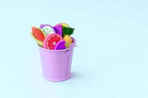 Various fresh fruits in small violet pail on blue background photo