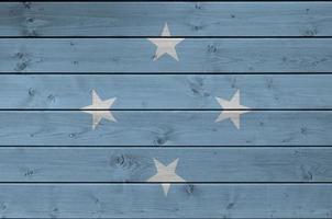 Micronesia flag depicted in bright paint colors on old wooden wall. Textured banner on rough background photo