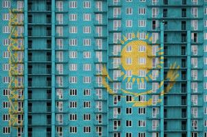 Kazakhstan flag depicted in paint colors on multi-storey residental building under construction. Textured banner on brick wall background photo