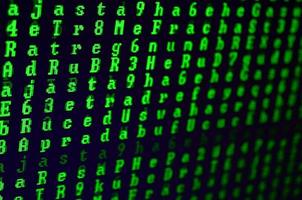 Macro shot of a glitch on the monitor of an office computer. The concept of introducing a virus into a personal data keeper. Stream of random green symbols on a black background photo