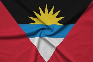 Antigua and Barbuda flag  is depicted on a sports cloth fabric with many folds. Sport team banner photo