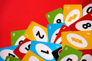 TERNOPIL, UKRAINE - MAY 15, 2022 Many colorful UNO game cards on red background. UNO is an American shedding-type card game that is played with a specially printed deck photo