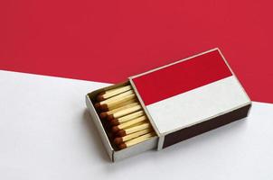 Indonesia flag  is shown in an open matchbox, which is filled with matches and lies on a large flag photo