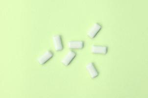 A few chewing gums lie on texture background of fashion pastel lime color paper photo