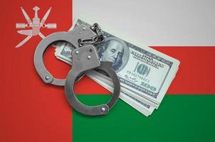 Oman flag  with handcuffs and a bundle of dollars. Currency corruption in the country. Financial crimes photo