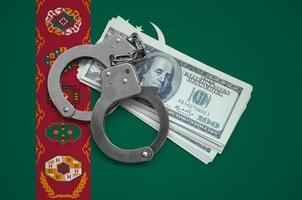 Turkmenistan flag  with handcuffs and a bundle of dollars. Currency corruption in the country. Financial crimes photo