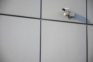 White surveillance camera built into the metal wall of the office building photo