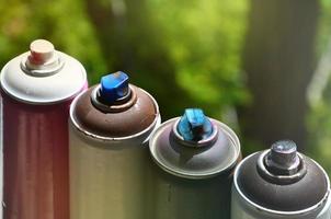 A few used aerosol paint sprayers lie on the windowsill in the workshop of a graffiti artist. The concept of street art and illegal drawing on the walls. Youth hobby photo