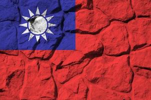 Taiwan flag depicted in paint colors on old stone wall closeup. Textured banner on rock wall background photo