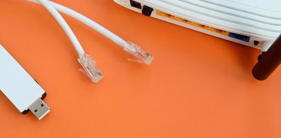 Internet router, portable USB wi-fi adapter and internet cable plugs lie on a bright orange background. Items required for internet connection photo