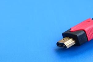 Black audio video HDMI computer cable on blue background. Close up of home entertainment connection cable for sound and video photo