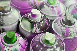 A lot of used spray cans of paint close-up. Dirty and smeared cans for drawing graffiti. The concept of a sweeping and careless drawing of paint. Creative art image photo